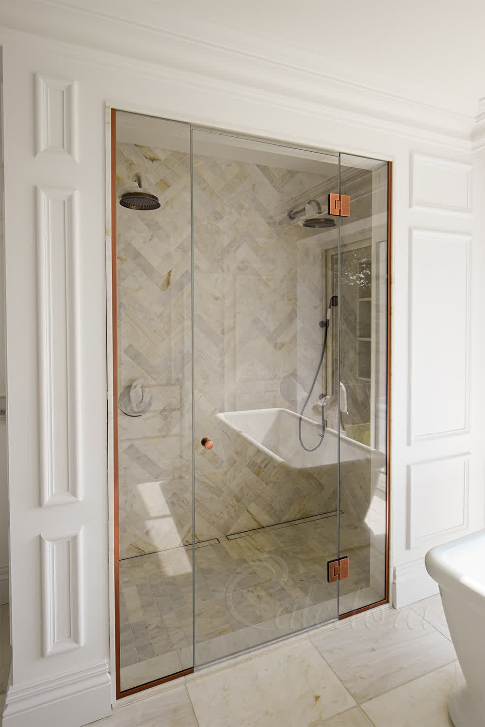 Frameless alcove shower enclosure with copper fixtures in Beaconsfield bathroom, viewed from the left side with closed door aligning with side panels