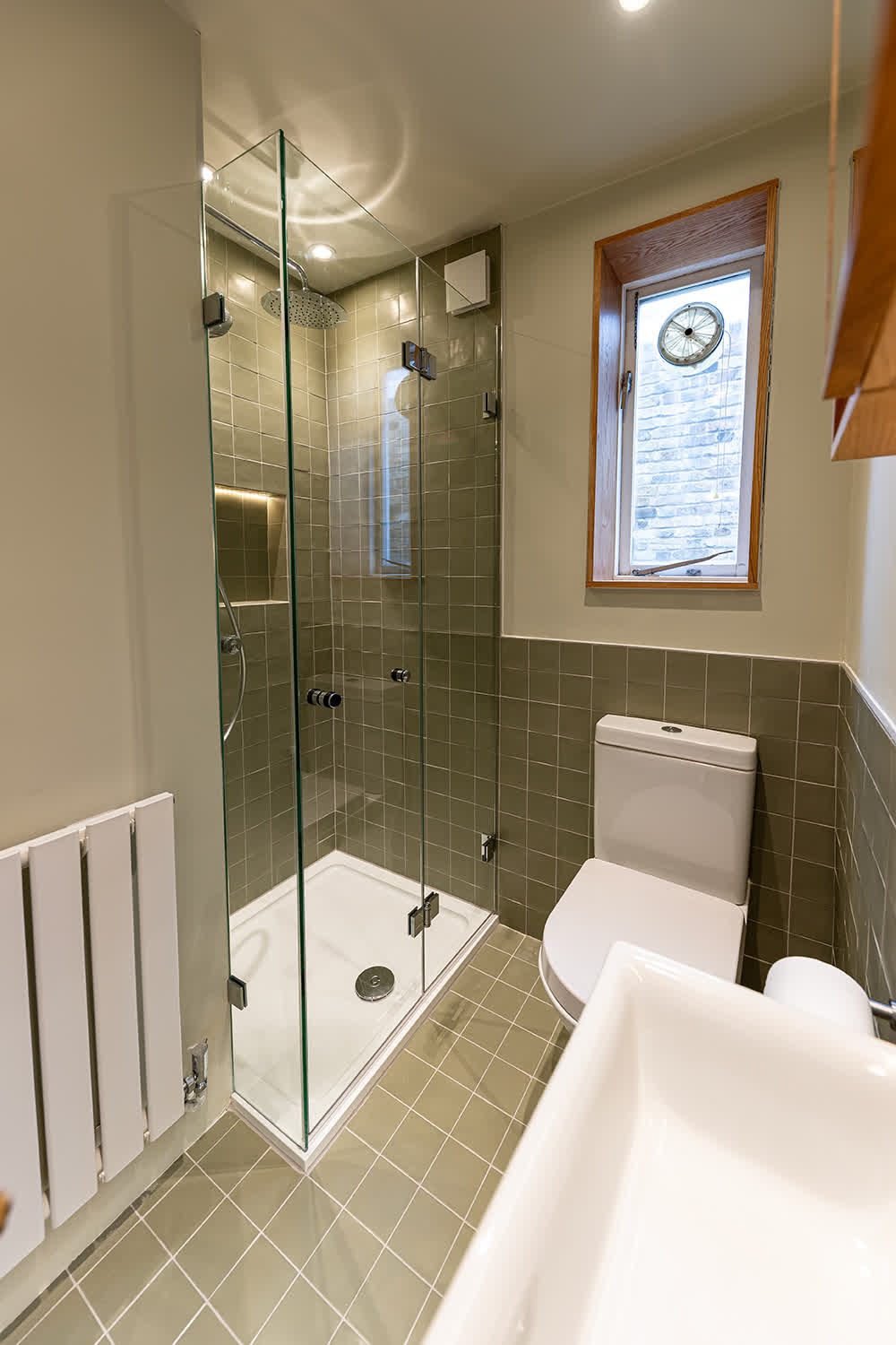 Frameless bifold shower enclosure with clear glass and chrome fittings in a compact London bathroom