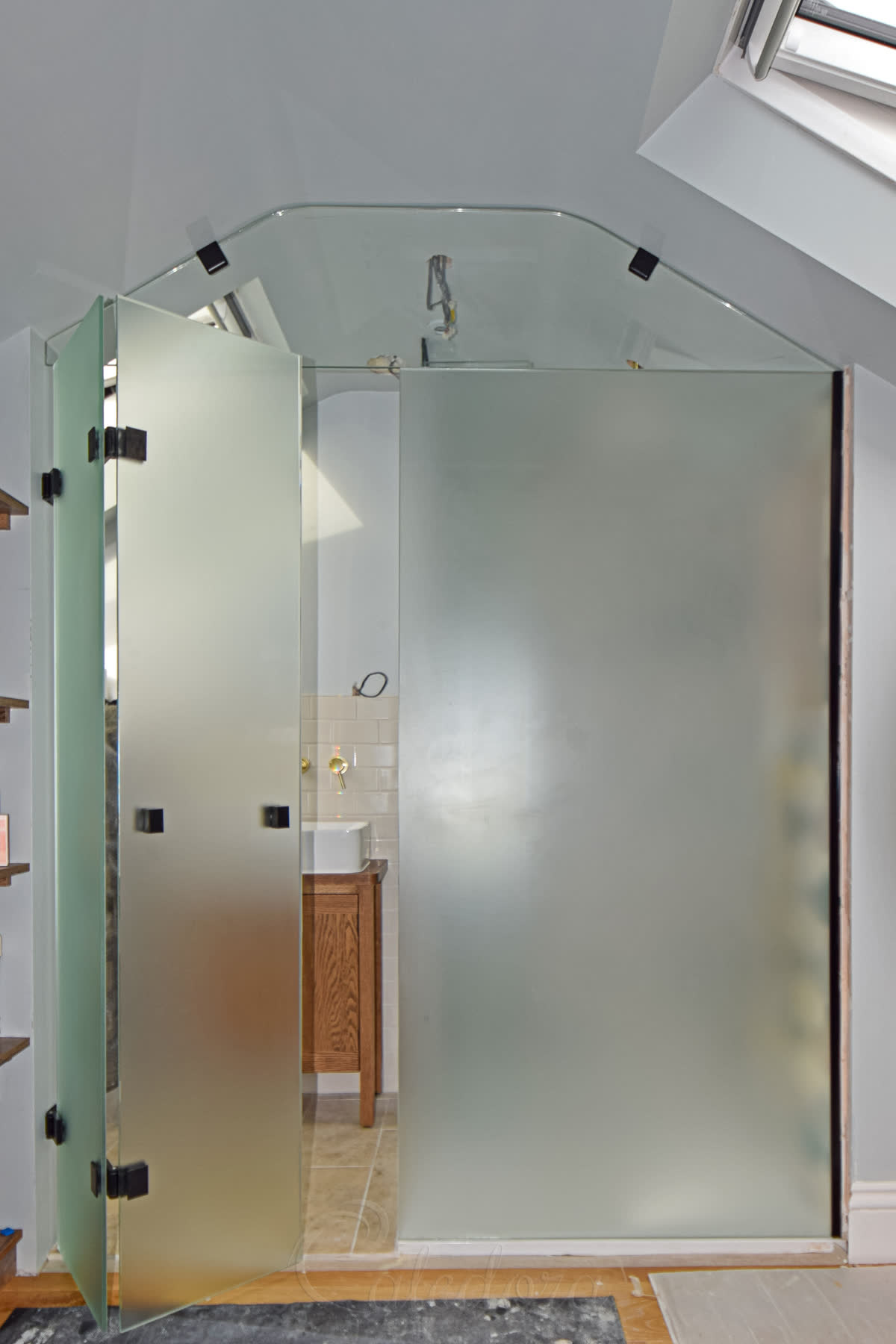 Black frosted bifold ensuite door partially open from bedroom showing dual system