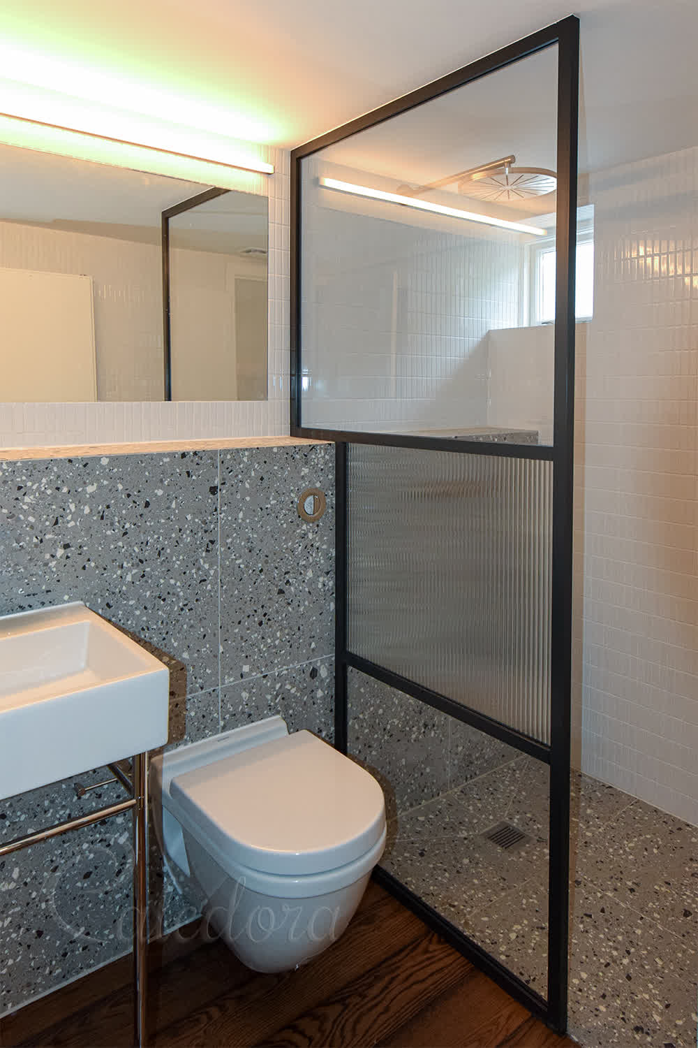 Black framed shower screen with fluted glass panel and clear sections showing modern bathroom design
