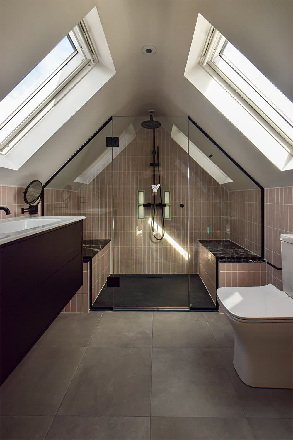 Shower enclosure glass panel notched around tiled bench with black U-channel fixings