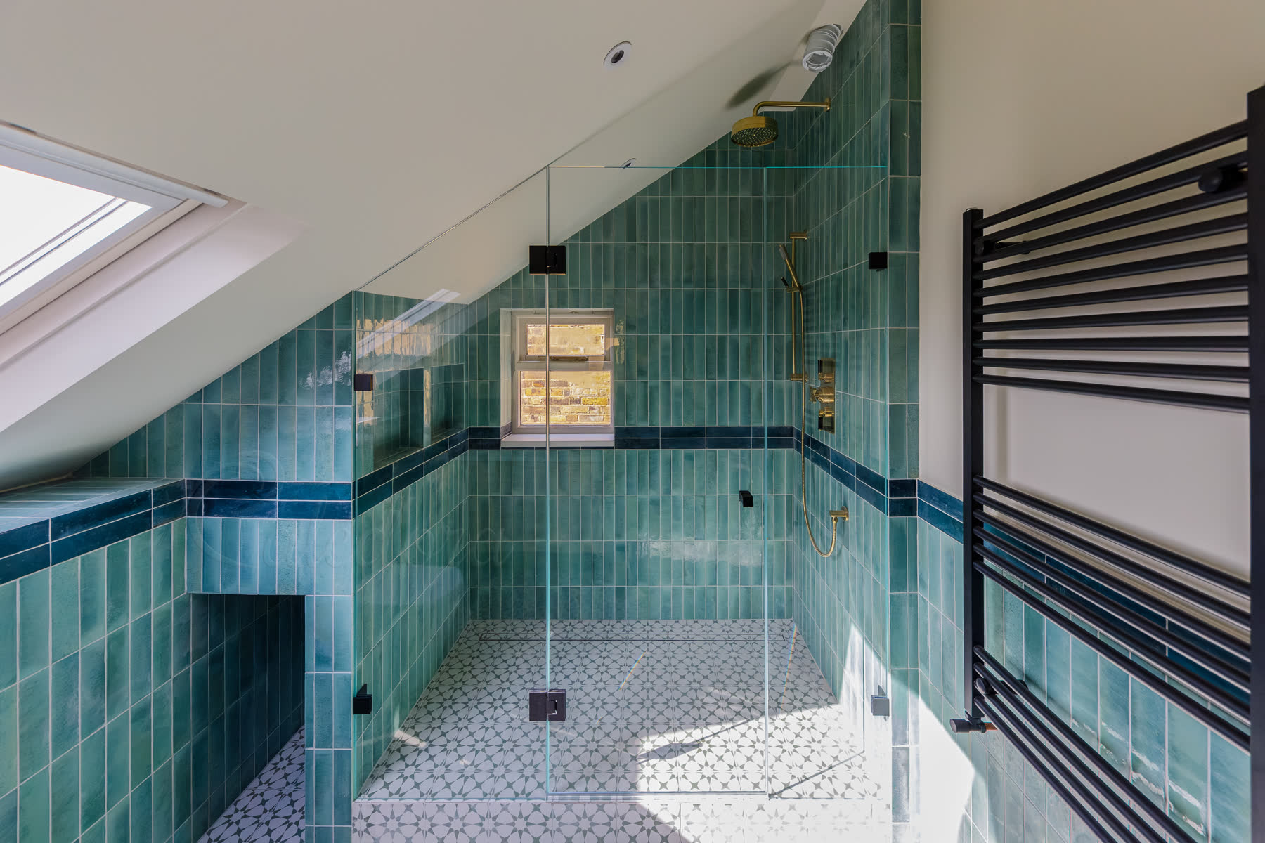 Full width bathroom view of black frameless shower with slanted ceiling and green tiles