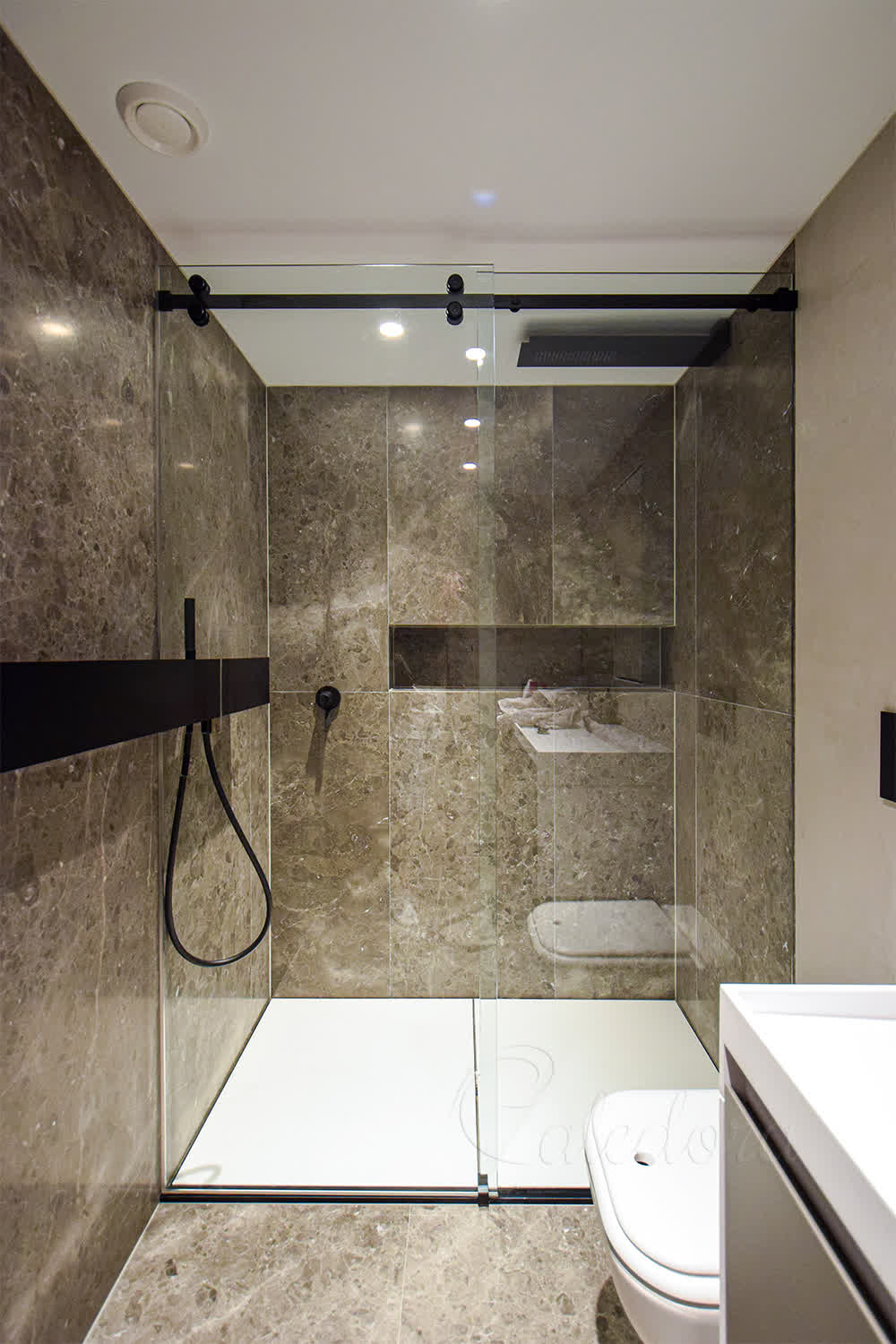 Black framed sliding shower door with custom cut-out to accommodate wall shelf in London bathroom