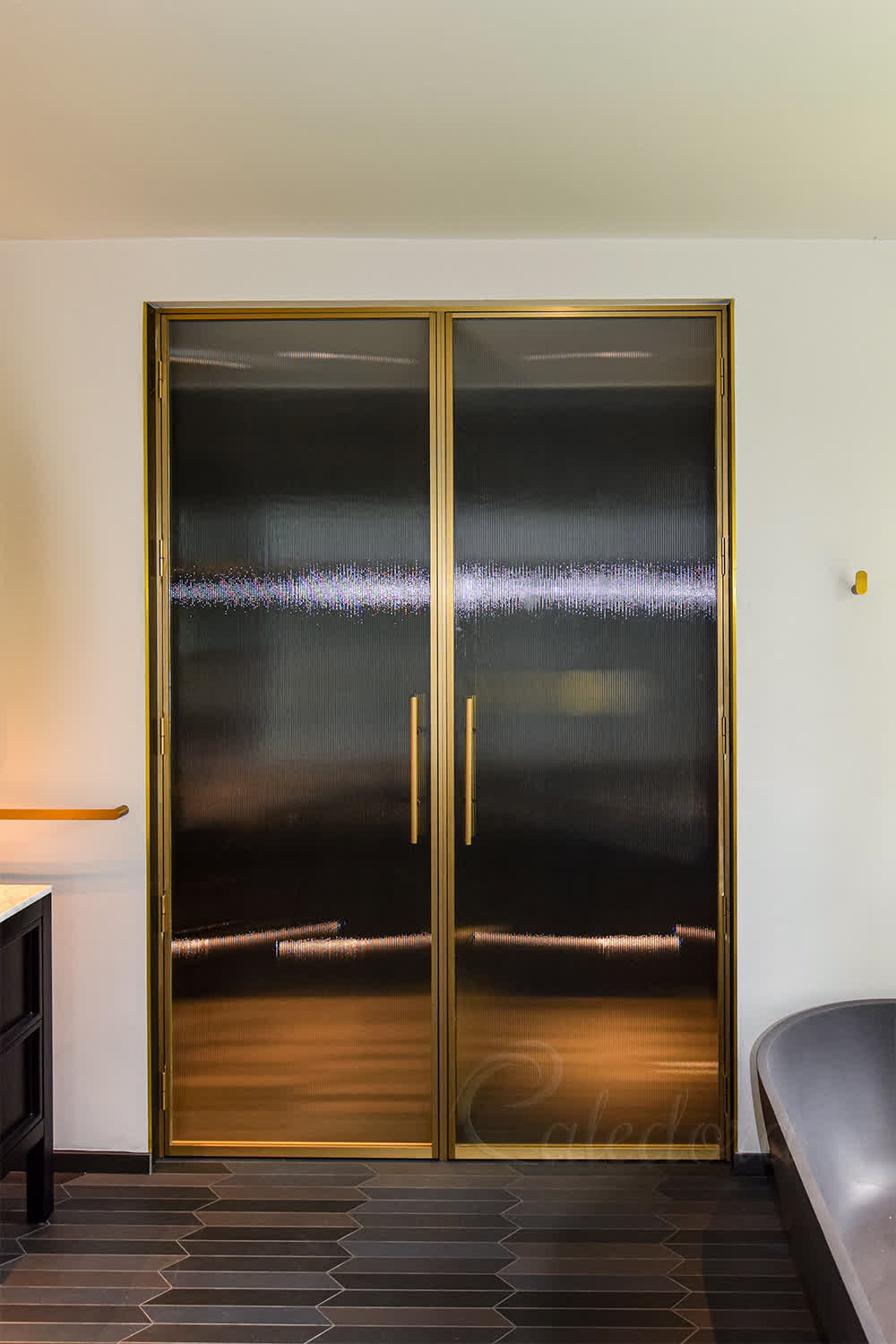 Brushed brass framed shower doors with fluted glass panels in a luxury Gloucester bathroom