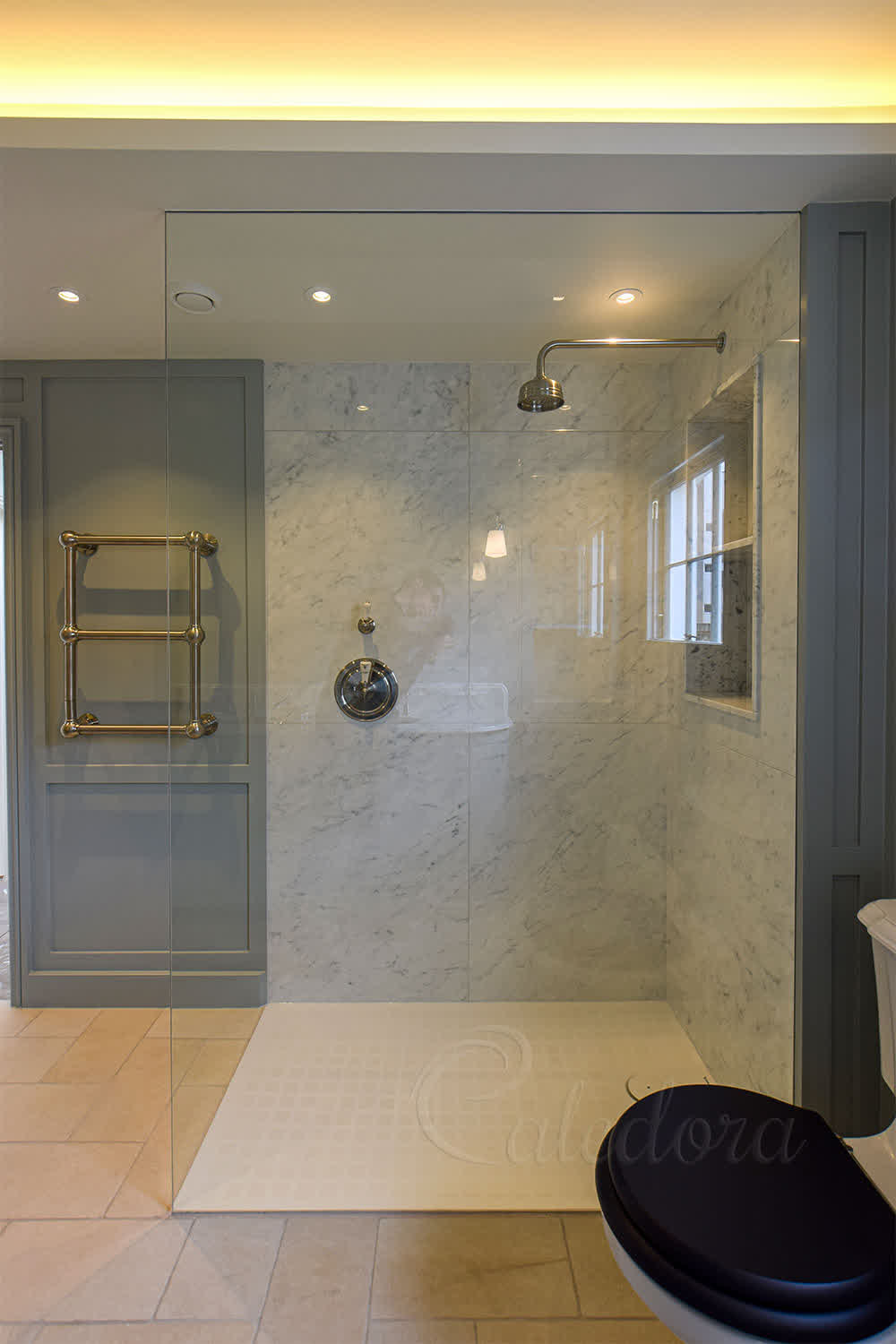 Frameless floor to ceiling shower screen recessed into marble wall with white shower tray