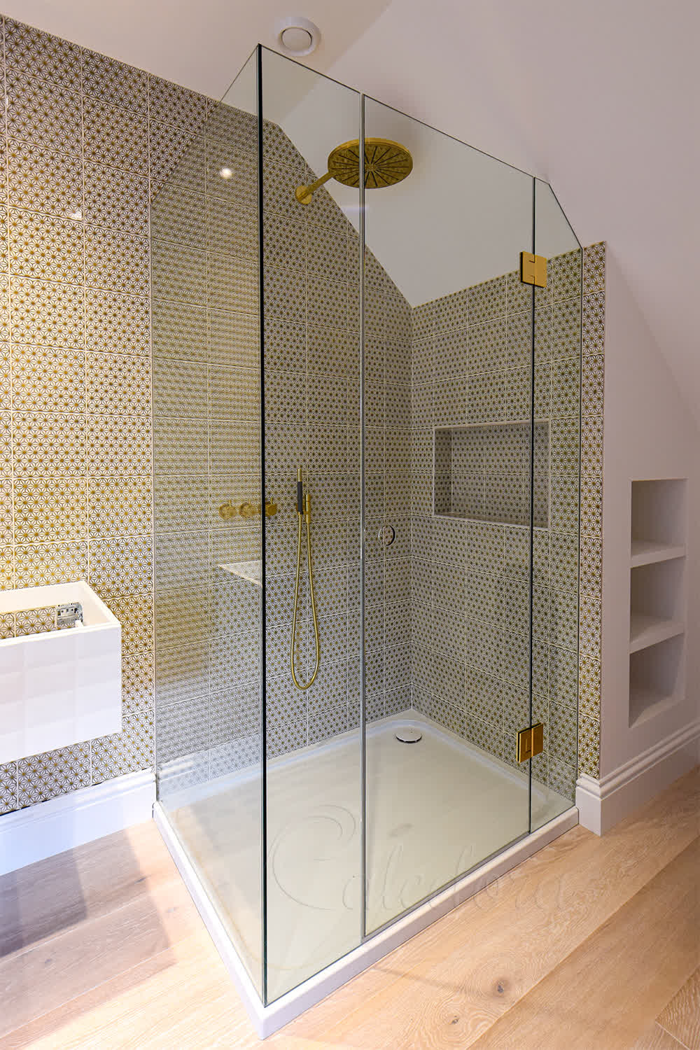 Brass fixtures and tile-aligned glass in frameless loft shower