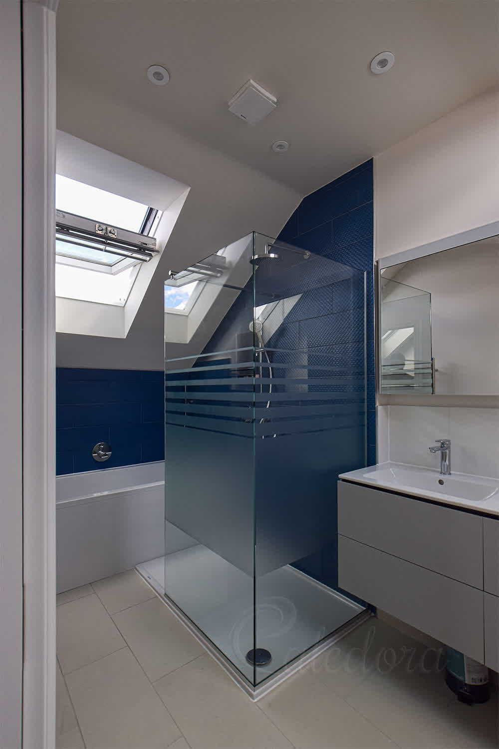 Frosted patterned shower screen in corner bathroom with gradual stripes and blue tiles
