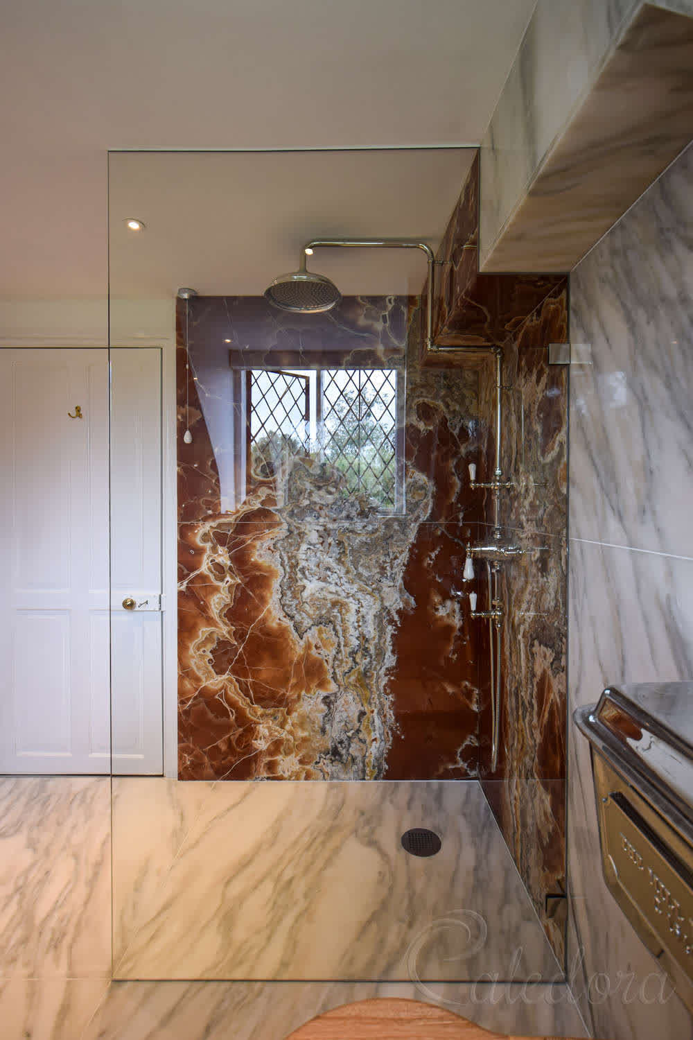 Polished chrome brackets securing full-height frameless shower screen in tiled bathroom