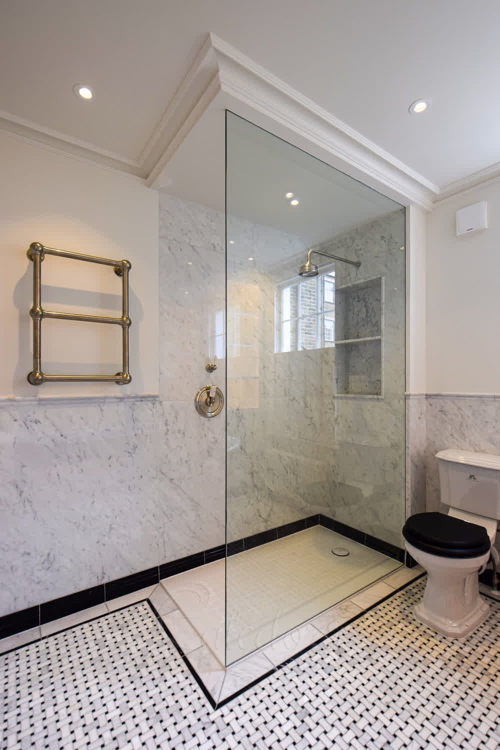 Frameless full height shower screen in clear glass recessed between marble and plastered wall