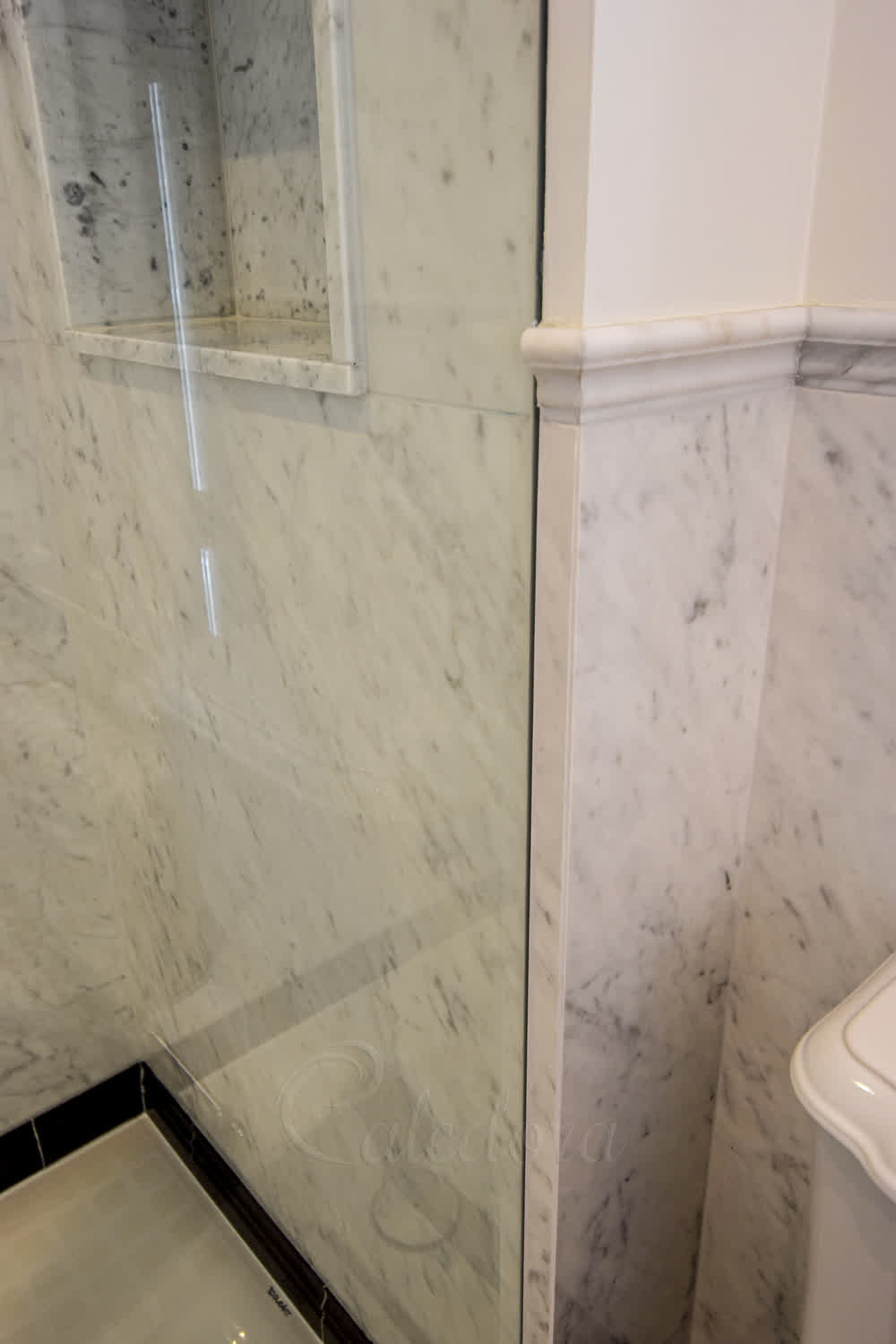 Large format frameless shower glass recessed into a tight wall space with minimal clearance