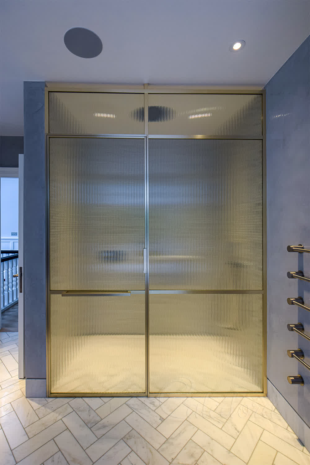 Framed brass shower enclosure with reeded glass and level floor access