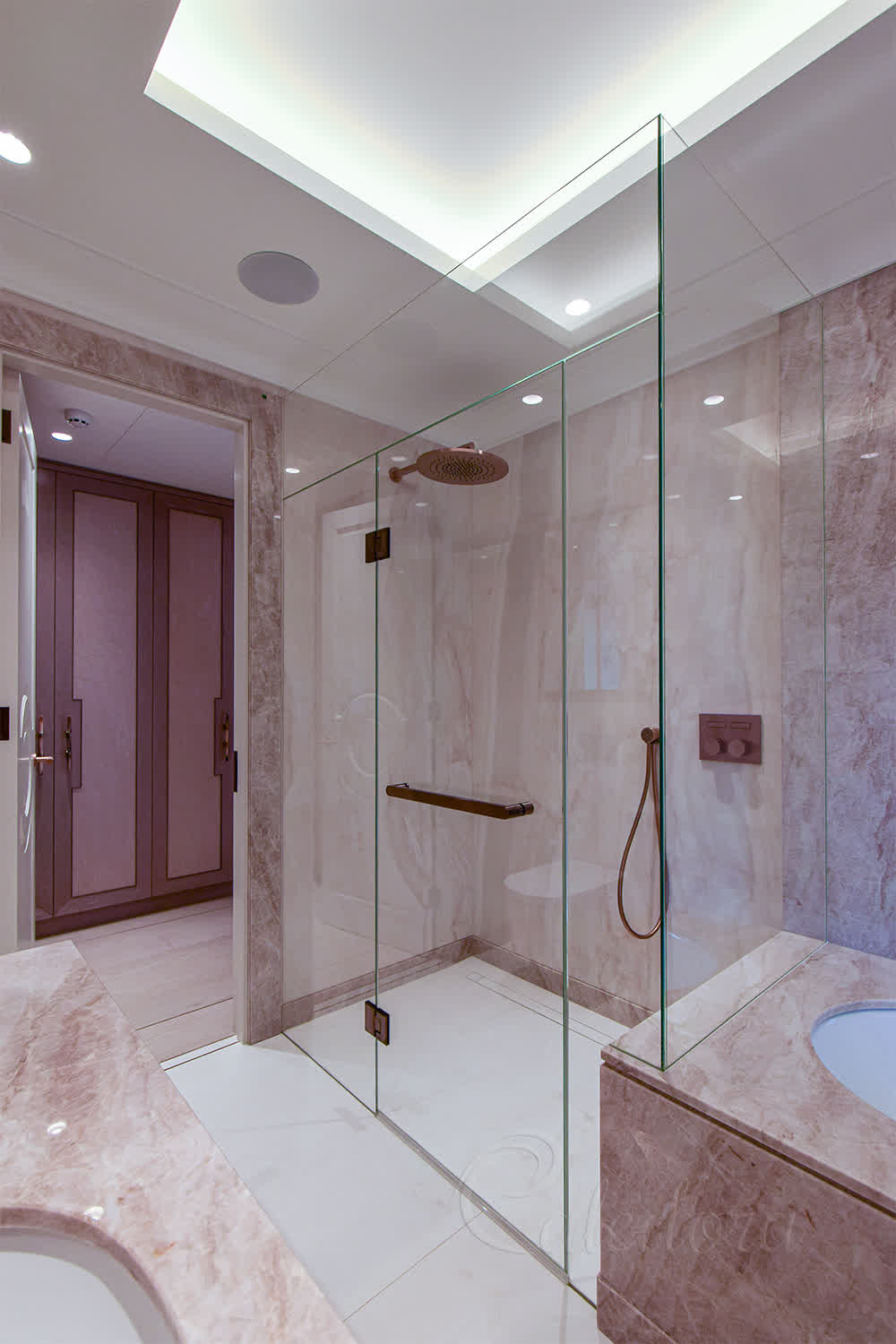 Frameless luxury shower enclosure with antique copper fixtures and recessed glass panels in a marble bathroom