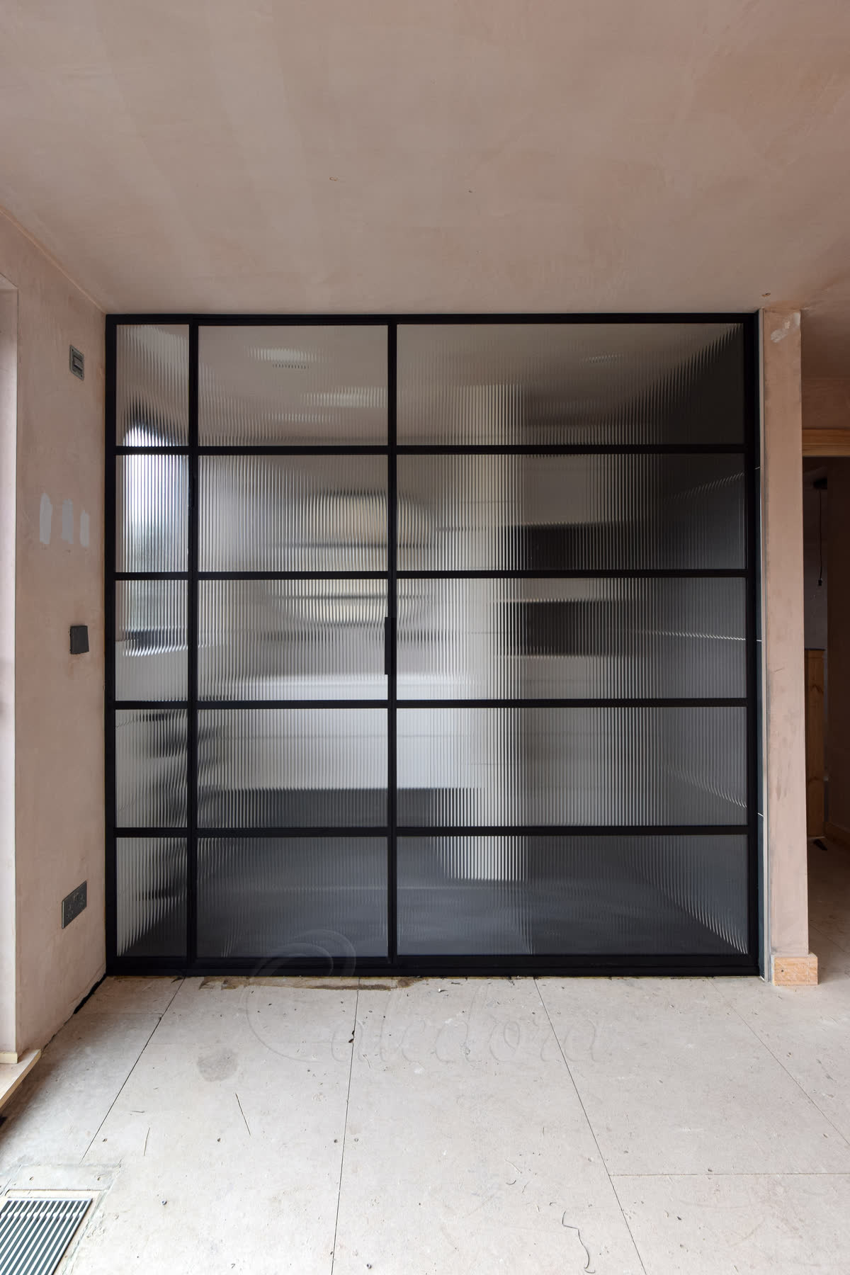 Black grid framed shower partition with ribbed glass panels providing privacy while allowing light in modern bathroom