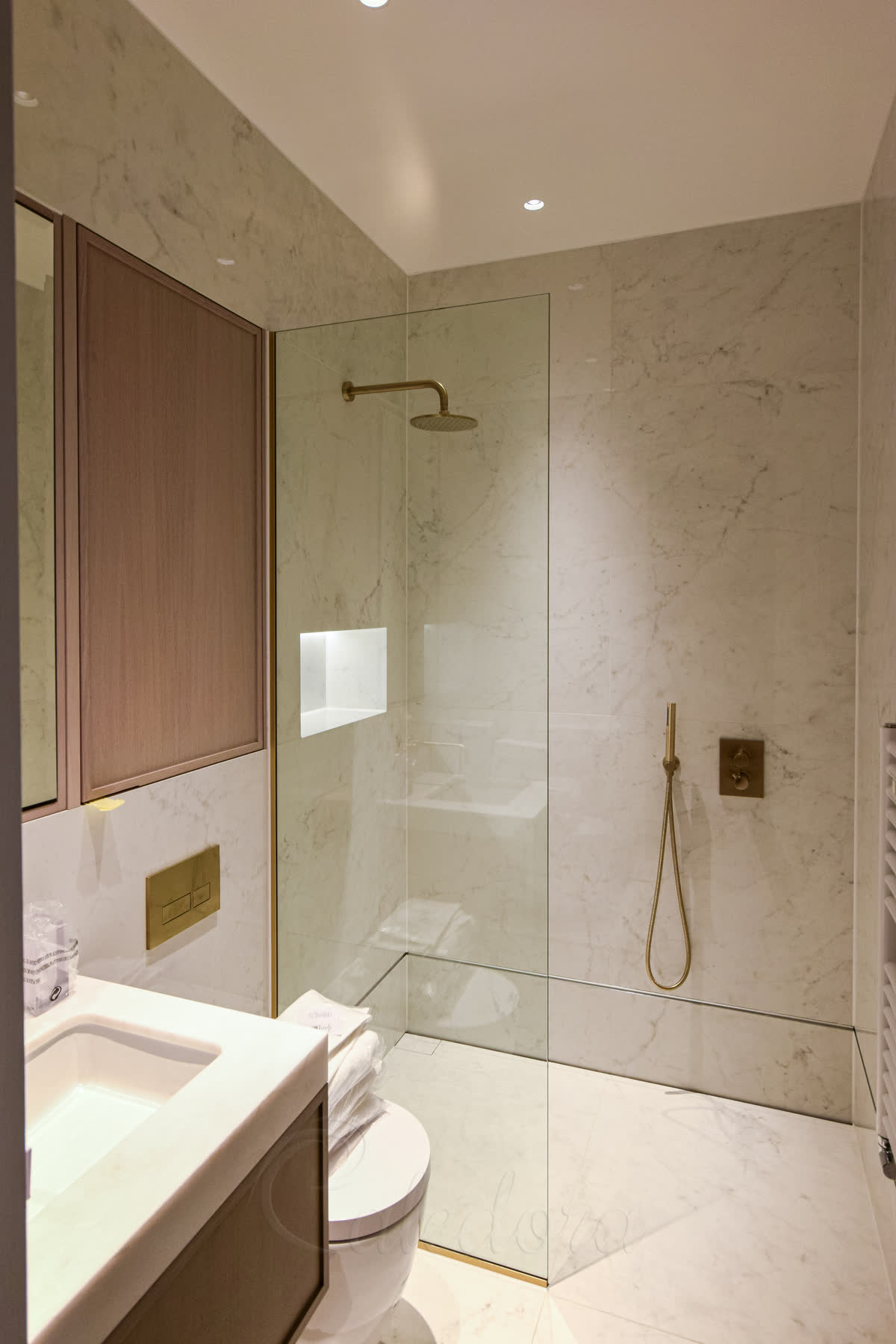 Short shower screen Cookham showing small glass panel with brass fixtures and marble tiles