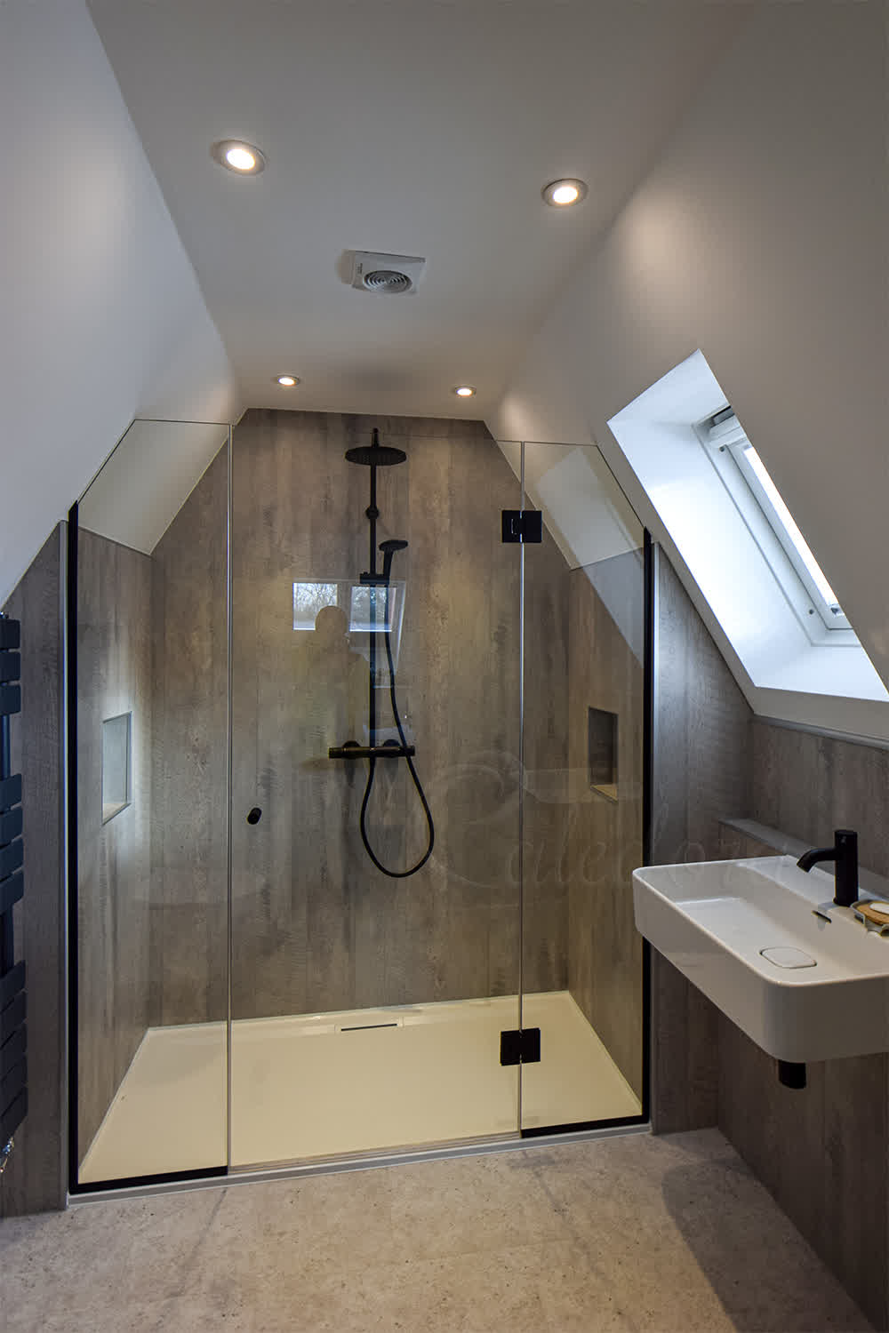 Custom loft shower enclosure with angled screens under slanted ceiling in converted attic