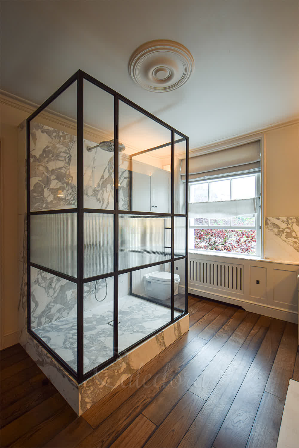 Luxury three-sided shower enclosure with black grid frame and fluted glass middle section in elegant marble bathroom