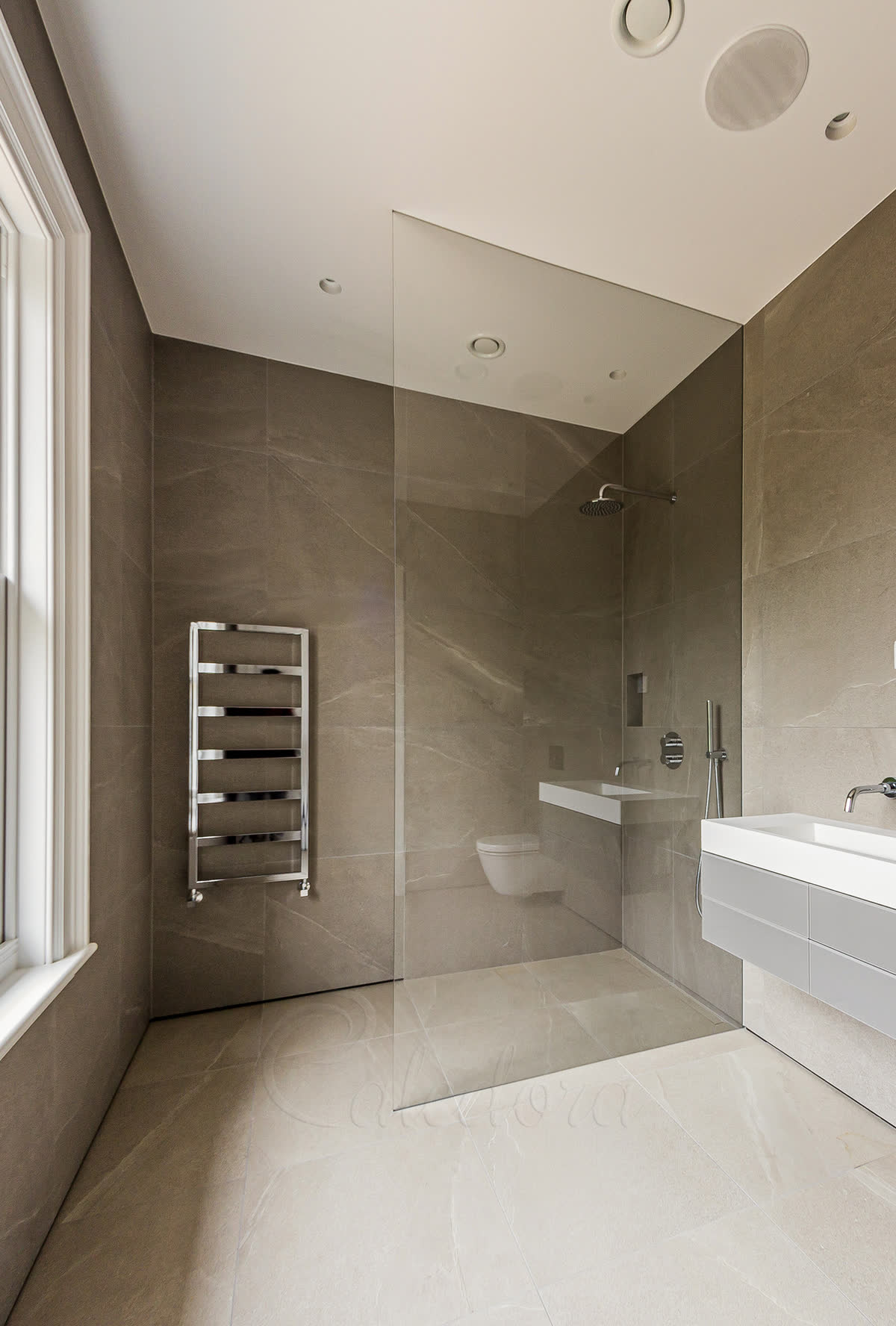 Walk-in shower glass panel recessed into wall and ceiling grooves with no visible metal fixings in modern bathroom