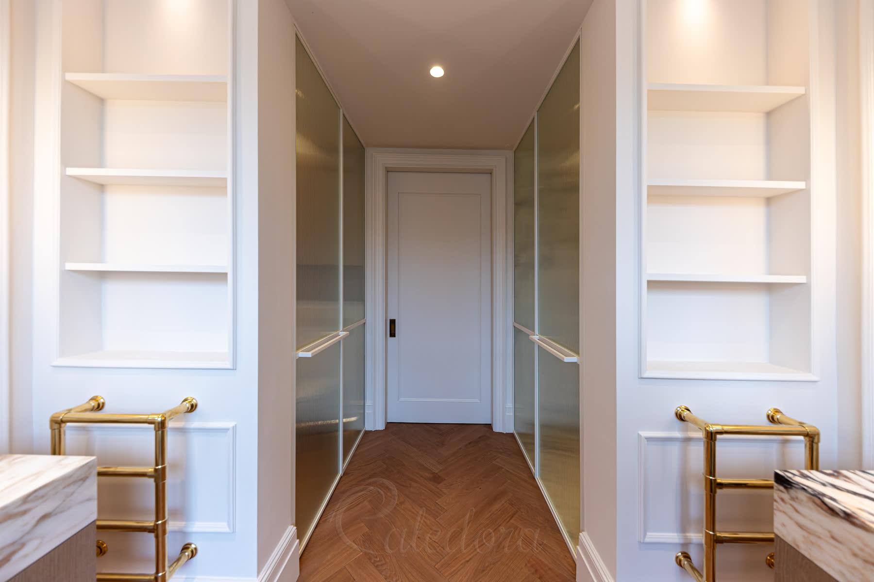 White framed fluted glass corridor between two matching shower partitions with brass towel warmers