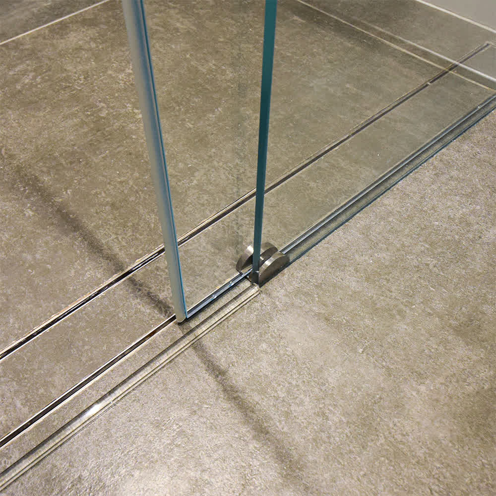 a sliding door guide in shower on a wet room floor